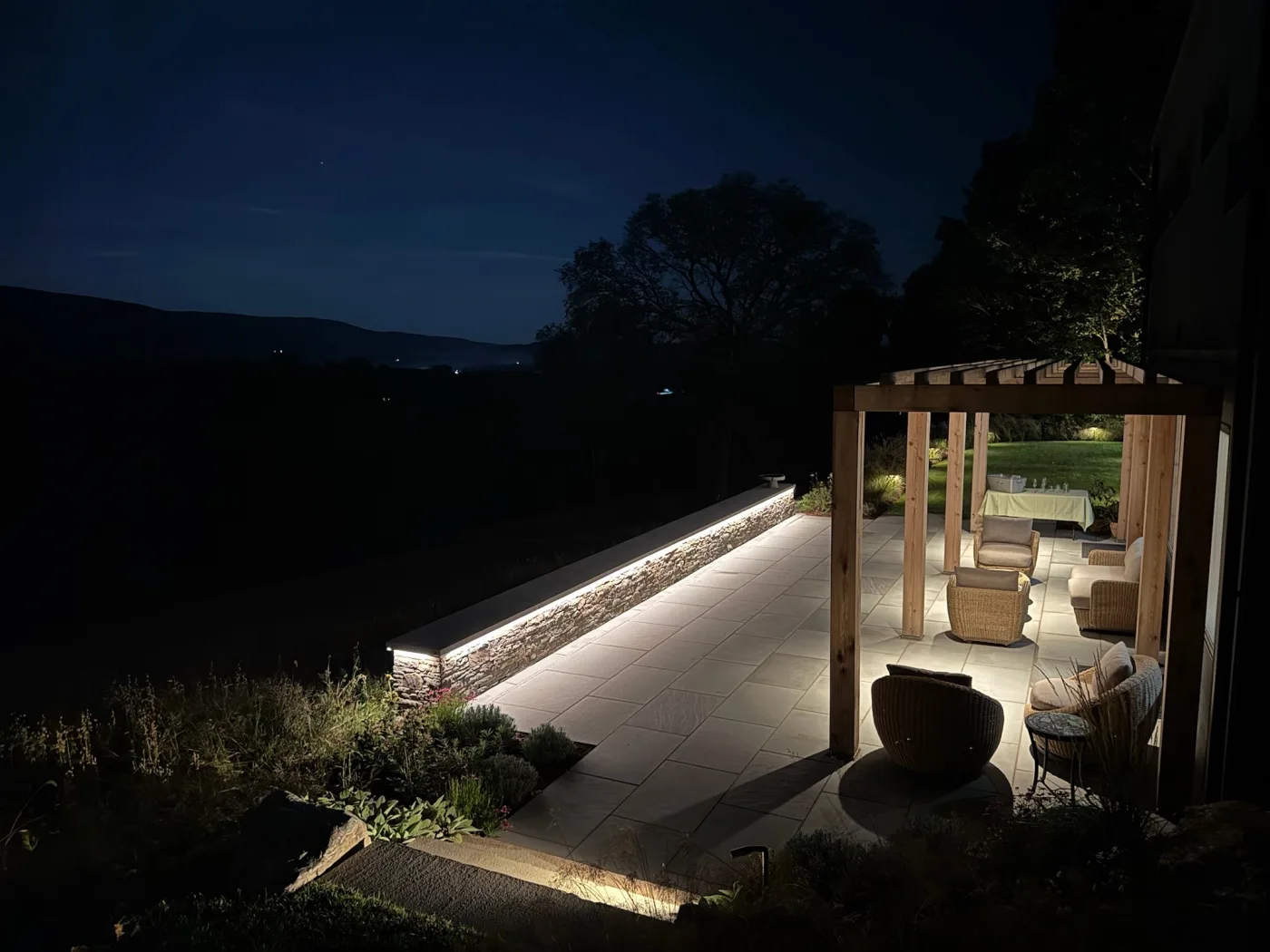 Illuminated patio, masonry wall, and outdoor living space at night.