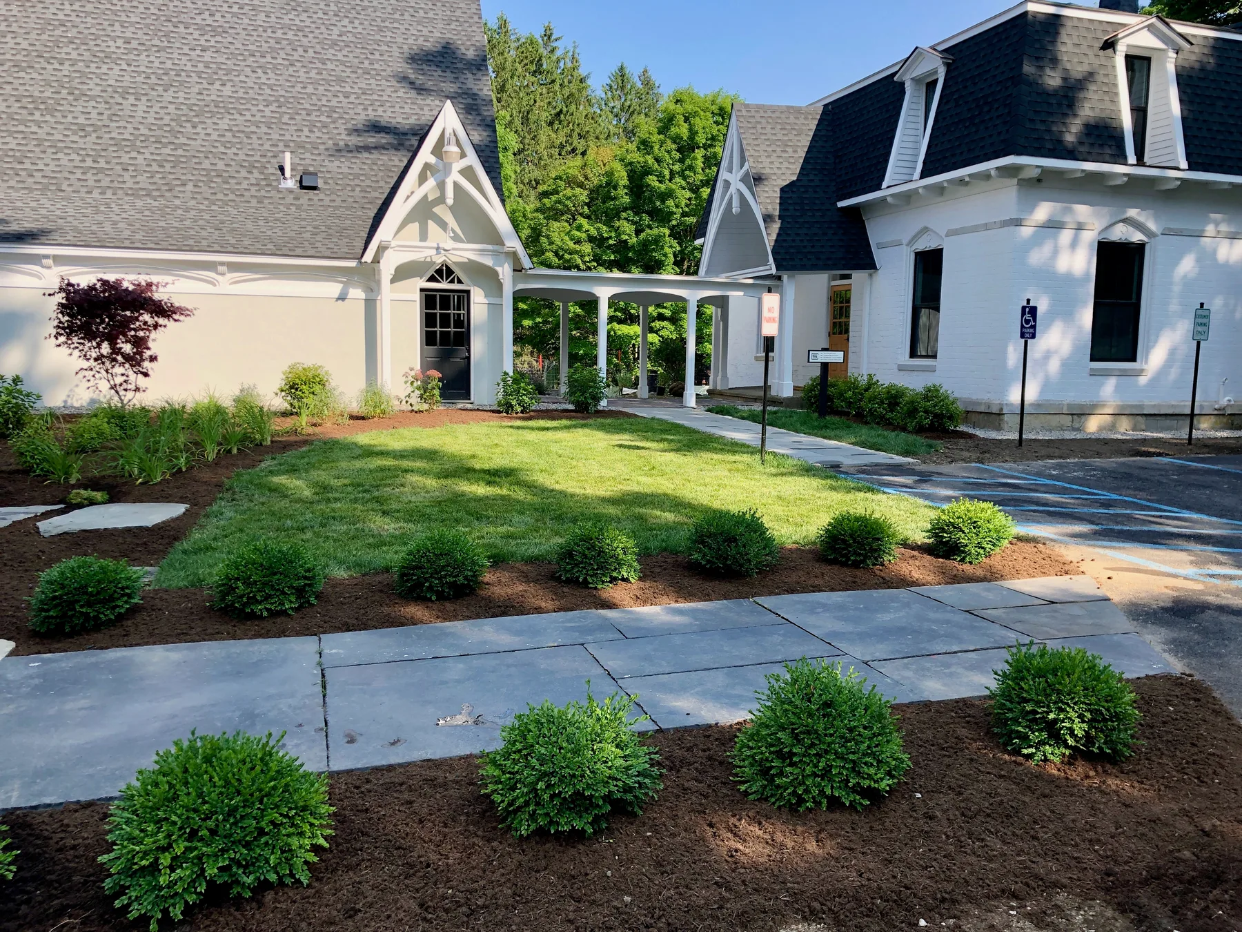 Commercial landscape installation with planting beds, sod lawn, and stone stepping areas.